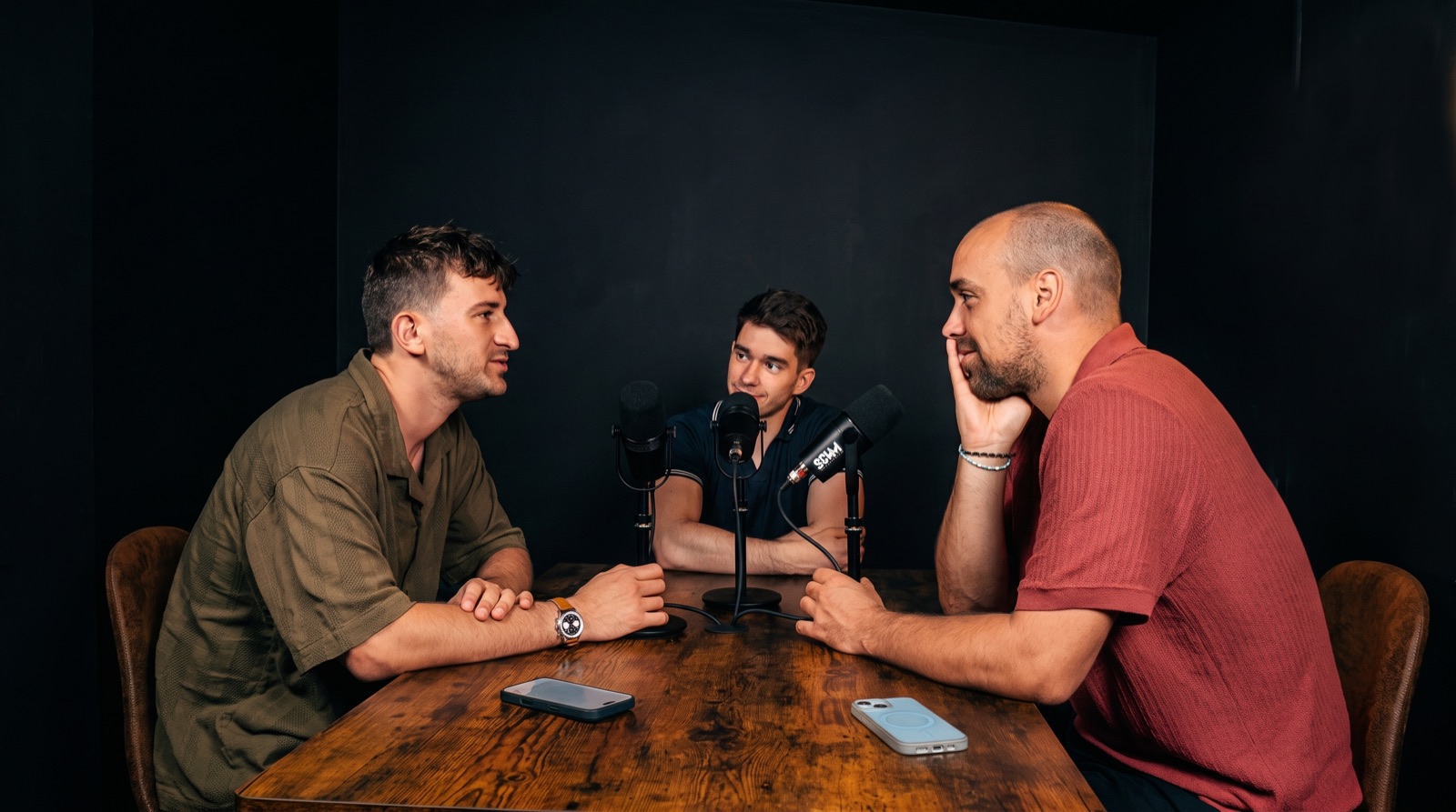 Trois intervenants en train d’enregistrer un podcast autour d’une table, chacun devant son micro